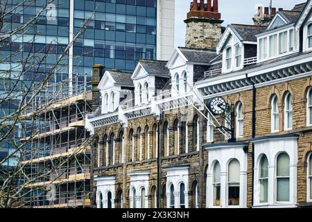 Traditional Victorian houses with ornate facades in front of modern glass office buildings, showcasing architectural contrast. Stock Photo