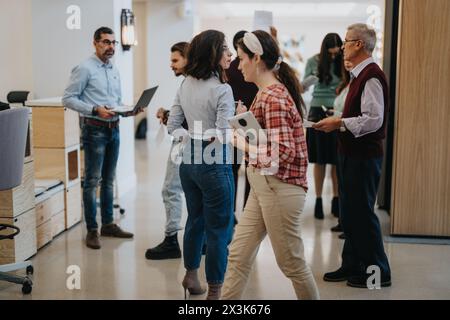 Multiracial business employees discussing projects in modern office corridor. Stock Photo