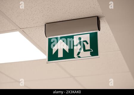 Standard exit sign on a clean light background, on the ceiling Stock Photo