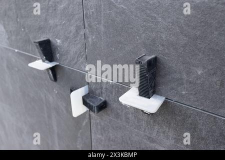 Close up of Plastic tile leveling system clips and wedges on Installed Ceramic tiles on construction site Stock Photo
