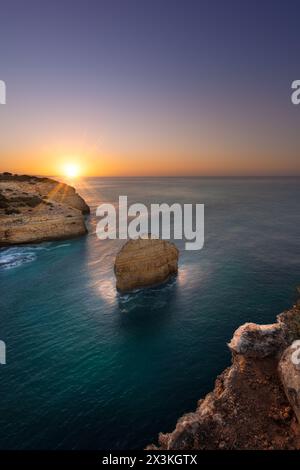 Sunrise over a typical scene of rock stack on the Algarve coast in Portugal Stock Photo