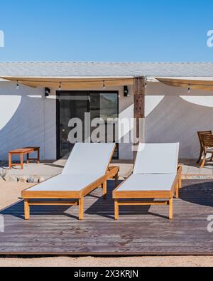 Two white wood outdoor chaise lounge chairs on a backyard deck Stock Photo
