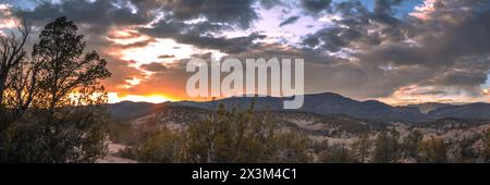 Sunset over some distant mountains near Reserve, New Mexico. Light can be seen in a canyon along with some orange hues in the sky. Desert panorama Stock Photo