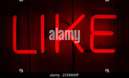 Four neon letter for the word Like. Red electric light on wooden background Stock Photo