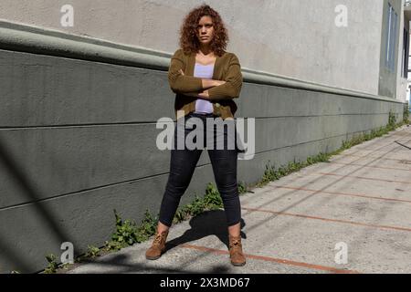 Latin American adult woman (34) of African descent with curly hair poses with arms crossed and serious attitude. Lifestyle concept. Stock Photo