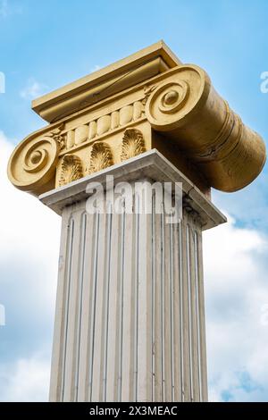 Top part of pillar, Greek-style columns with golden top, exterior detail. Greek-style columns with golden tops against blue sky. Travel photo, nobody Stock Photo