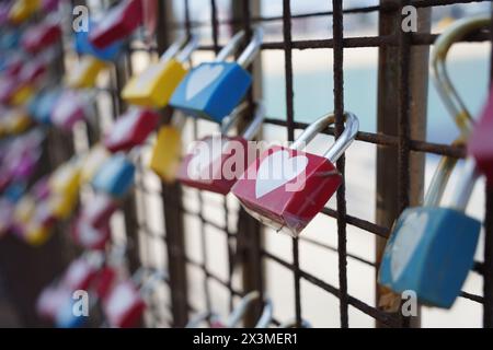 Colorful padlocks in the shape of heart on the fence. Stock Photo