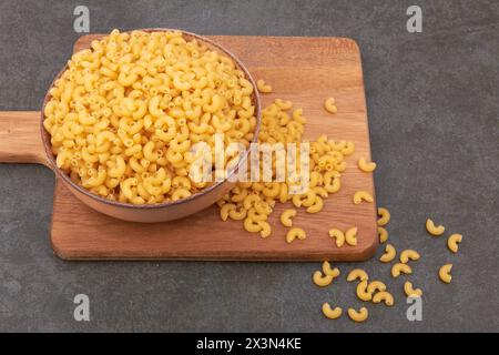 Elbow macaroni in bowl on black background Stock Photo