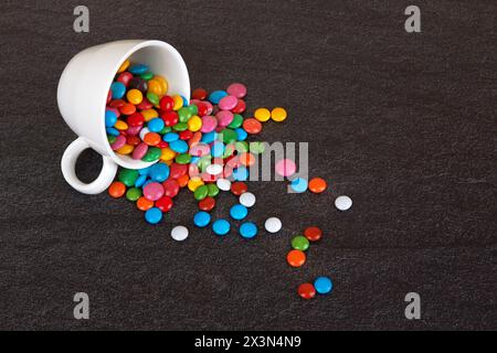 Colorful chocolate buttons on bkack stone surface Stock Photo