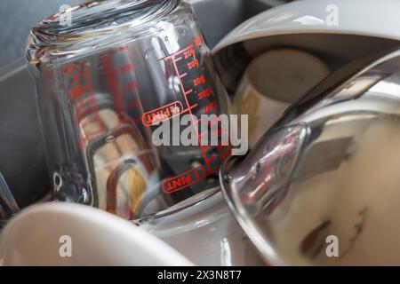 Clean washed glass measuring cup with plates sitting drying rack. Stock Photo