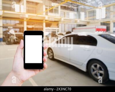 Female hand holding mobile smart phone on car service centre or garage blur background Stock Photo