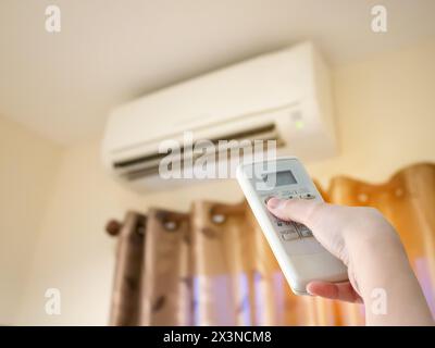 Hand hold remote control directed on the air conditioner Stock Photo
