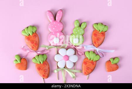 Easter gingerbread cookies in the shape of hares and carrots on pink background. Easter greeting card. Top view Stock Photo