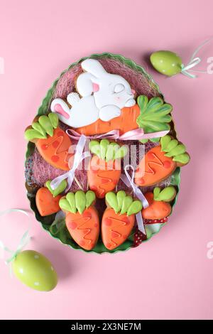 Easter gingerbread cookies in the shape of bunny and carrots on pink background. Easter greeting card. View from above Stock Photo