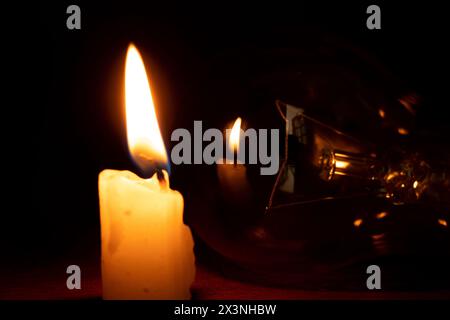 Incandescent lamp and candle in the dark at home, without light Stock Photo