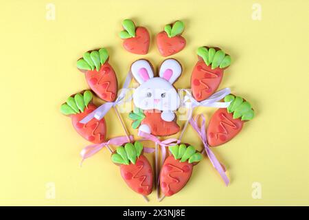 Easter gingerbread cookies in the shape of bunny and carrots on yellow background. Easter greeting card. View from above Stock Photo