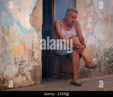 Portrait of an old man sat on a chair in a doorway in the backstreets of the Old Town, Trinidad, Cuba. Stock Photo