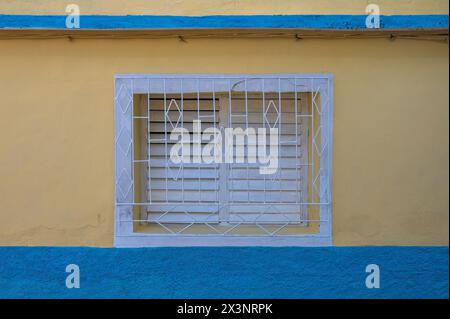 Brightly painted walls and metal grilles over windows of older houses in the backstreets of Trinidad, Cuba. Stock Photo