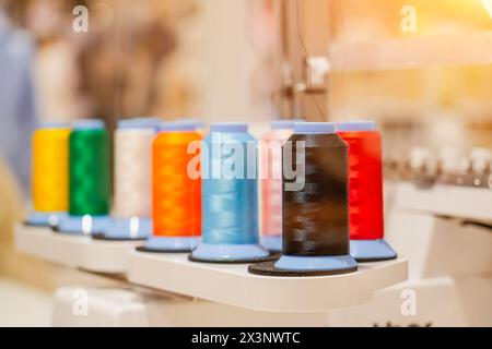 spools of colored thread installed on an automatic digital sewing machine. Stock Photo