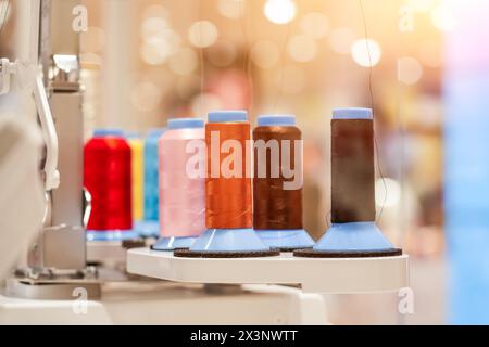 spools of colored thread installed on an automatic digital sewing machine. Stock Photo
