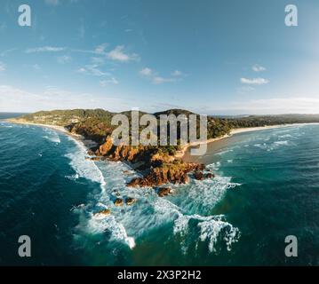 Byron Bay lighthouse and the pass high on the rocky headland - the most eastern point of Australian continent facing Pacific ocean in elevated aerial Stock Photo