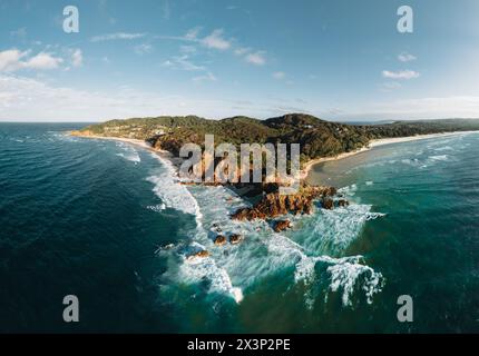 Byron Bay lighthouse and the pass high on the rocky headland - the most eastern point of Australian continent facing Pacific ocean in elevated aerial Stock Photo