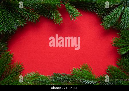 Red bright Christmas background. Winter frame of green branch on the textured fabric background. Stock Photo