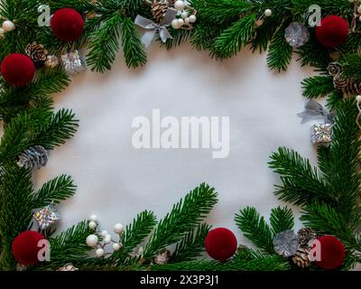White background and Christmas tree spruce for frame with gifts, red ball, cones. Copy space. Top view. Stock Photo