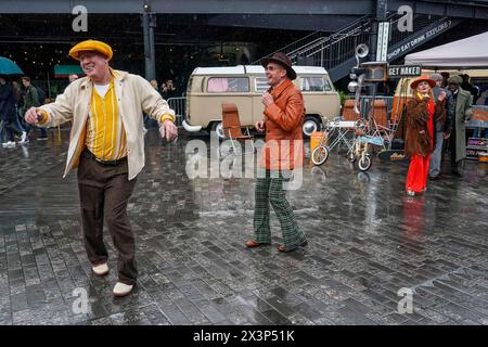 People dance in the rain at a Classic Car Boot sale at Kings Cross in London. Picture date: Sunday April 28, 2024. Stock Photo