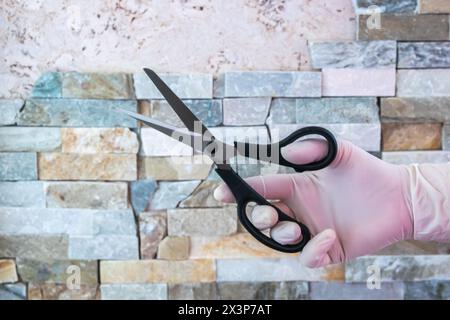 Scissors in the hand with rubber glove. Steel shears for cutting. Stock Photo
