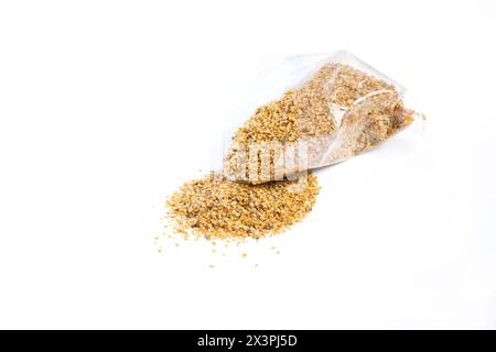 Dry food Daphnia for aquarium fish poured out of a plastic bag on a white background Stock Photo