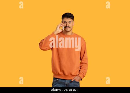 Man in Orange Sweater Talking on Smartphone Stock Photo