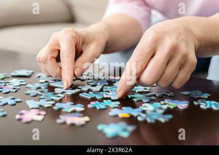 Cropped of Woman Placing Puzzle Piece on Table Stock Photo
