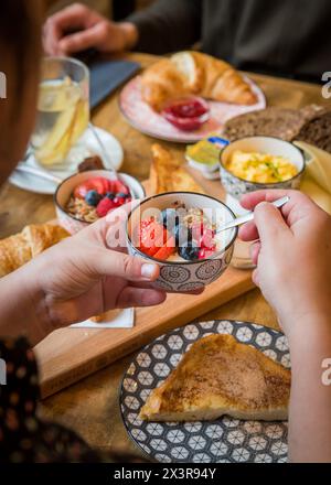 Breakfast of yogurt, fruit, croissants, bread, eggs and French toast being eaten at a bakery café Stock Photo