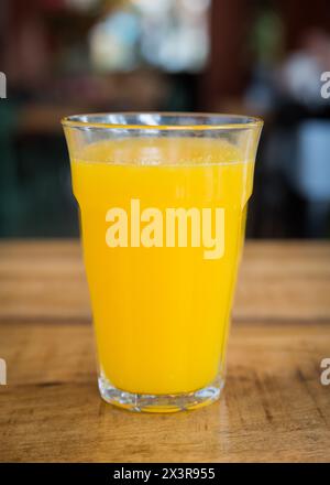 Freshly squeezed orange juice in a glass on a wooden table in a café restaurant Stock Photo