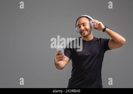 Man Wearing Headphones and Holding Cell Phone Stock Photo