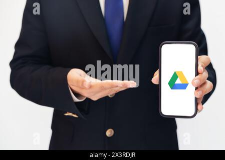 Man using Google Dribe on Mobile and pointing towards it with other hand, editorial background. Cloud Storage providing company google drive backdrop Stock Photo