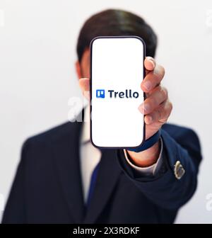 Mobile App of Trello shown by a suited person, application is used to manage task and team or organization. Editorial backdrop Stock Photo