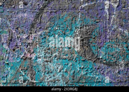 Mixed shades of cyan, black and purple colour dripped paint on old concrete wall background. Natural paintbrush strokes and textured rough cement. Stock Photo