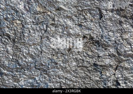 The nice, old rough and cracked concrete wall is painted with silver shining paint. Stock Photo