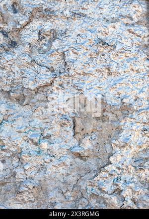 The crumbling plaster wall is painted with silver glitter paint have a bluish and yellowish tint. Stock Photo
