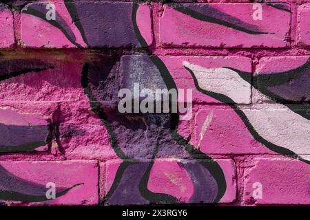 The texture of a pink brick wall painted with different-toned pink and purple patterns. Stock Photo