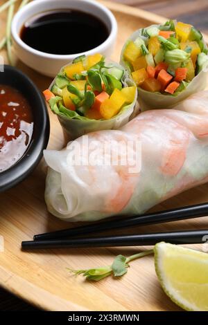Tasty spring rolls and sauces on wooden plate, closeup Stock Photo