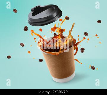 Aromatic coffee splashing in takeaway paper cup and flying roasted beans on turquoise background Stock Photo