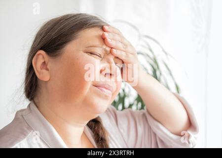 diseased mature woman experiences severe headache, holding head, Hot flashes during menopause, Decreased memory and concentration, feeling nervous, Fe Stock Photo