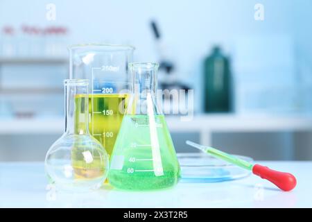 Laboratory analysis. Different glassware with liquids on white table indoors Stock Photo