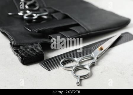 Hairdresser tools. Professional scissors, combs and leather organizer on white table, closeup Stock Photo