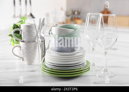 Many different clean dishware, glasses, cups and cutlery on white marble table indoors Stock Photo