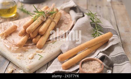 Traditional italian breadsticks grissini with rosemary, olive oil and sesame seeds on wooden countertop. Stock Photo