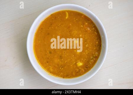 Delicious red lentil or masoor dal bhuna or ghono dal in a white bowl on wooden background. Stock Photo